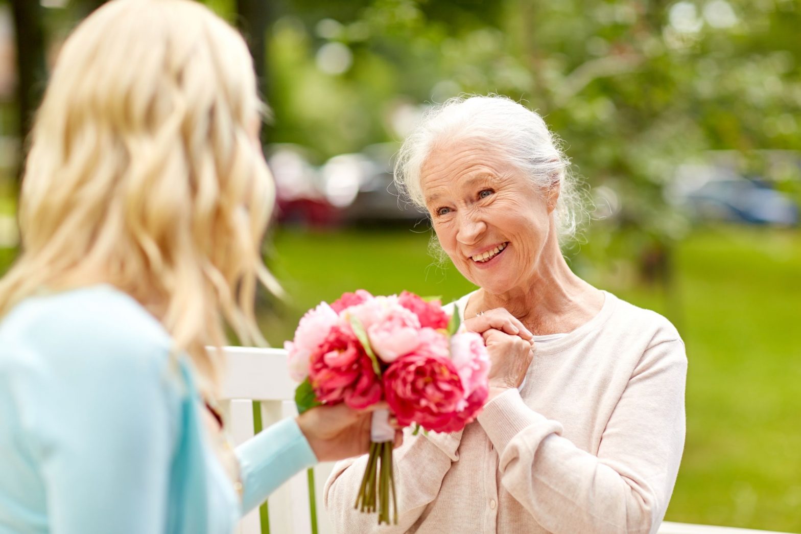 woman handing elderly woman flowers