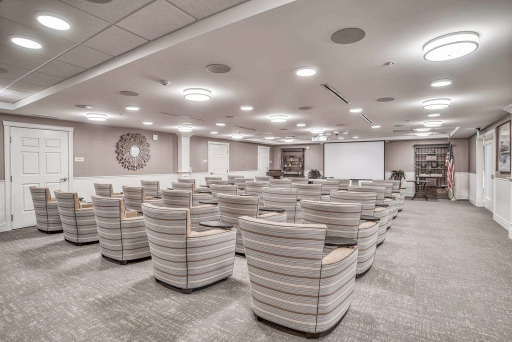 modern conference room with rows of striped armchairs, a projector, and a large screen