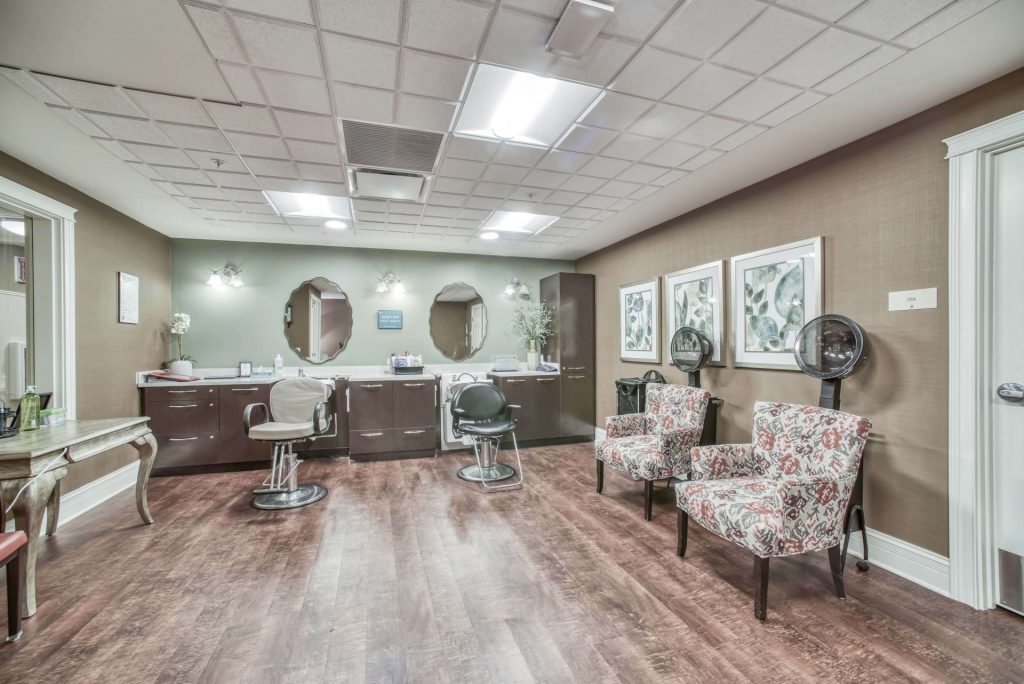 A modern hair salon with styling chairs, mirrors, hair dryers, and decorative wall art.