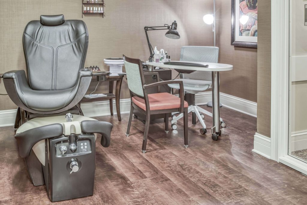 A modern nail salon pedicure and manicure station with chairs and equipment on wood flooring.
