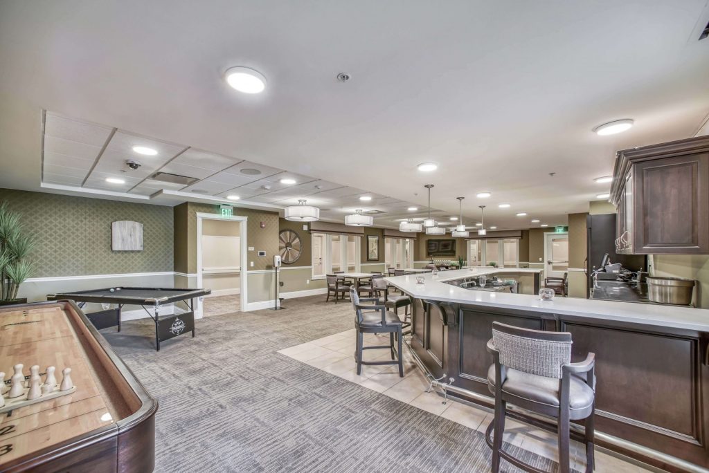 Recreation room with a bar counter, table tennis, shuffleboard, and seating areas.