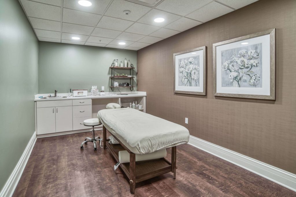 A serene massage room with a treatment table, soft lighting, and calming wall art in neutral tones.