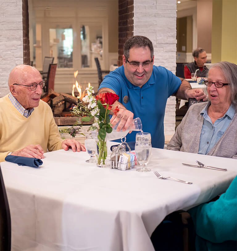Seniors getting water at dinner from a staff member