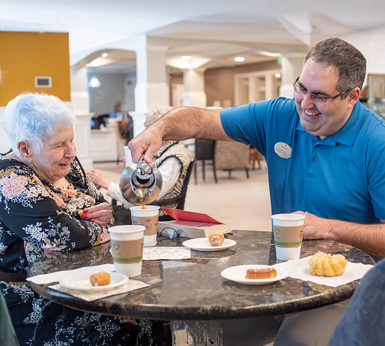 Senior woman getting tea from a staff member