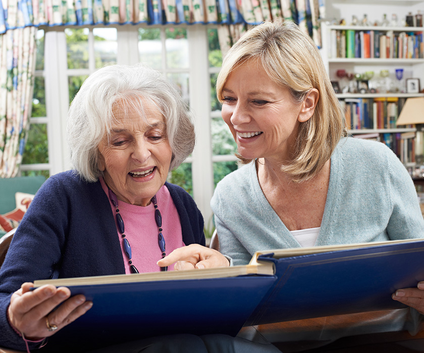 Senior woman and adult daughter looking through photo book